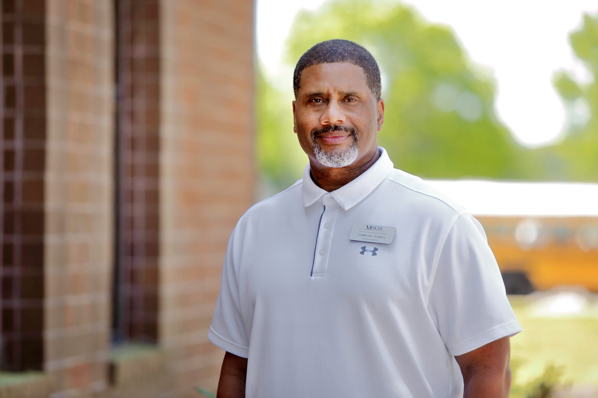 A Mercer teacher candidate stands in front of a brick building.