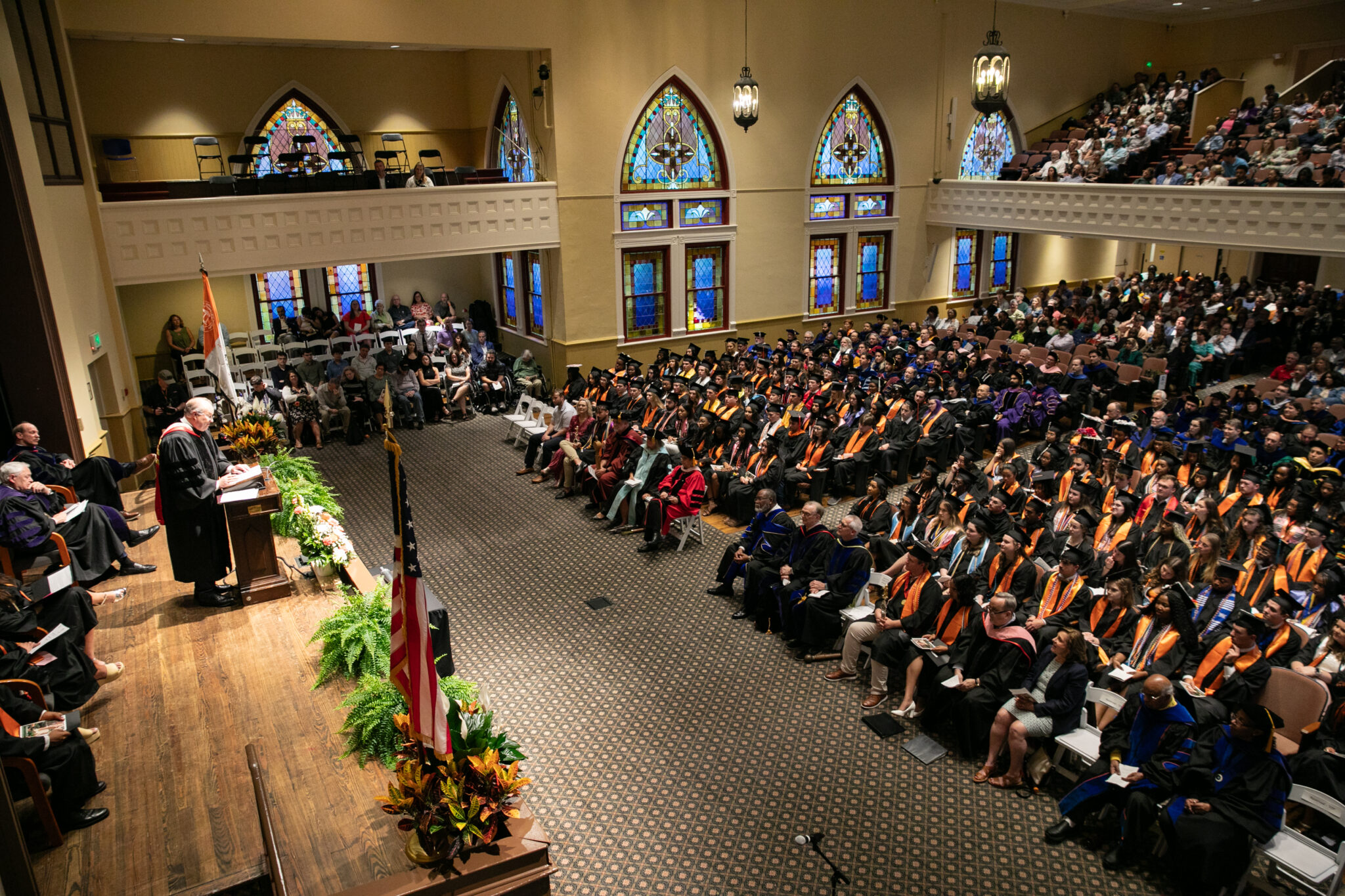 Mercer graduates wearing graduation regalia are seated in Toney Auditorium.