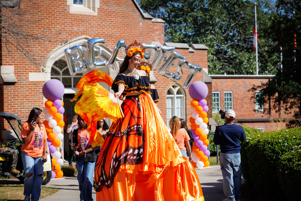 A stilt walker in an elaborate orange monarch butterfly costume performs at Mercer University's BearFest outdoor celebration.