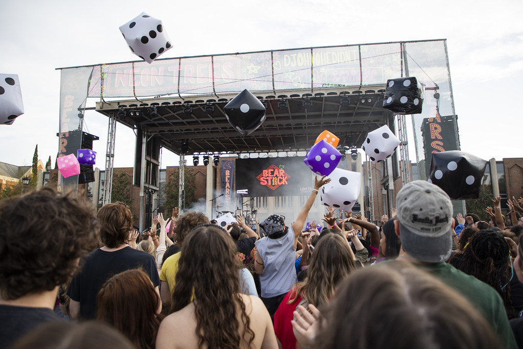 A crowd of students tosses giant inflatable dice in the air at Mercer University's outdoor BearStock music festival concert.