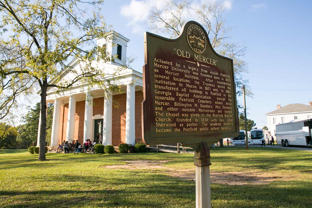 A Georgia historical marker for "Old Mercer" stands in front of a white-columned brick chapel in Penfield, where Mercer University was founded in 1833.