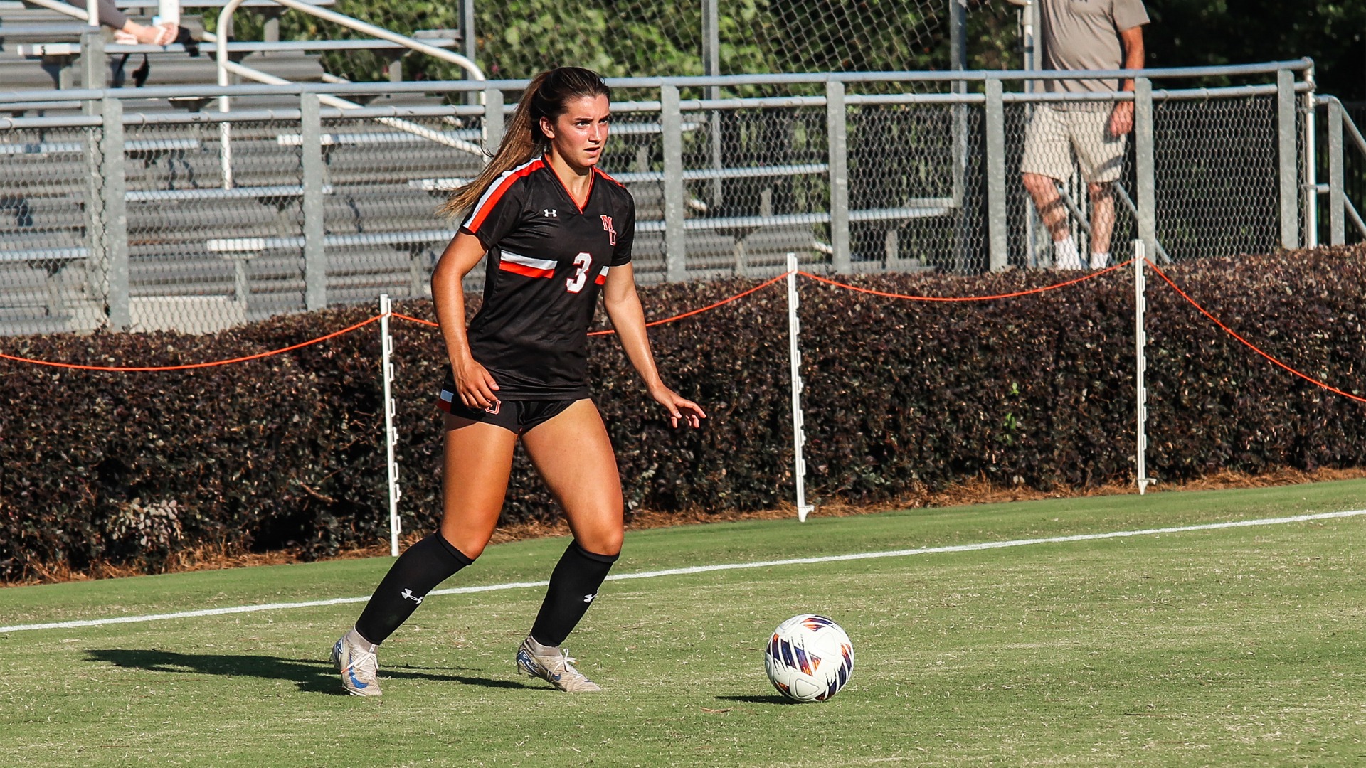 A Mercer women's soccer player looks downfield while dribbling a ball.