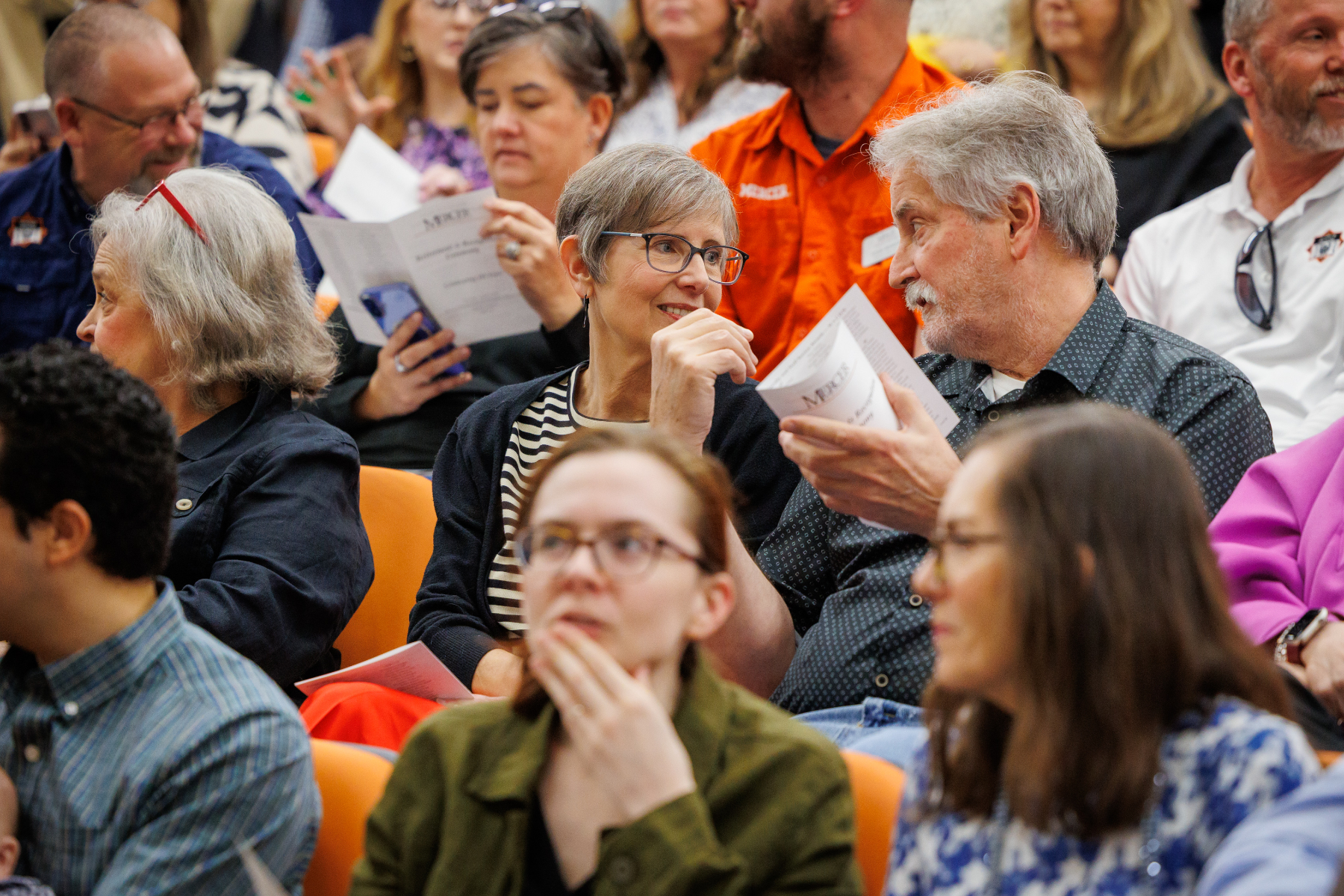 Mercer employee sit and talk in an auditorium.
