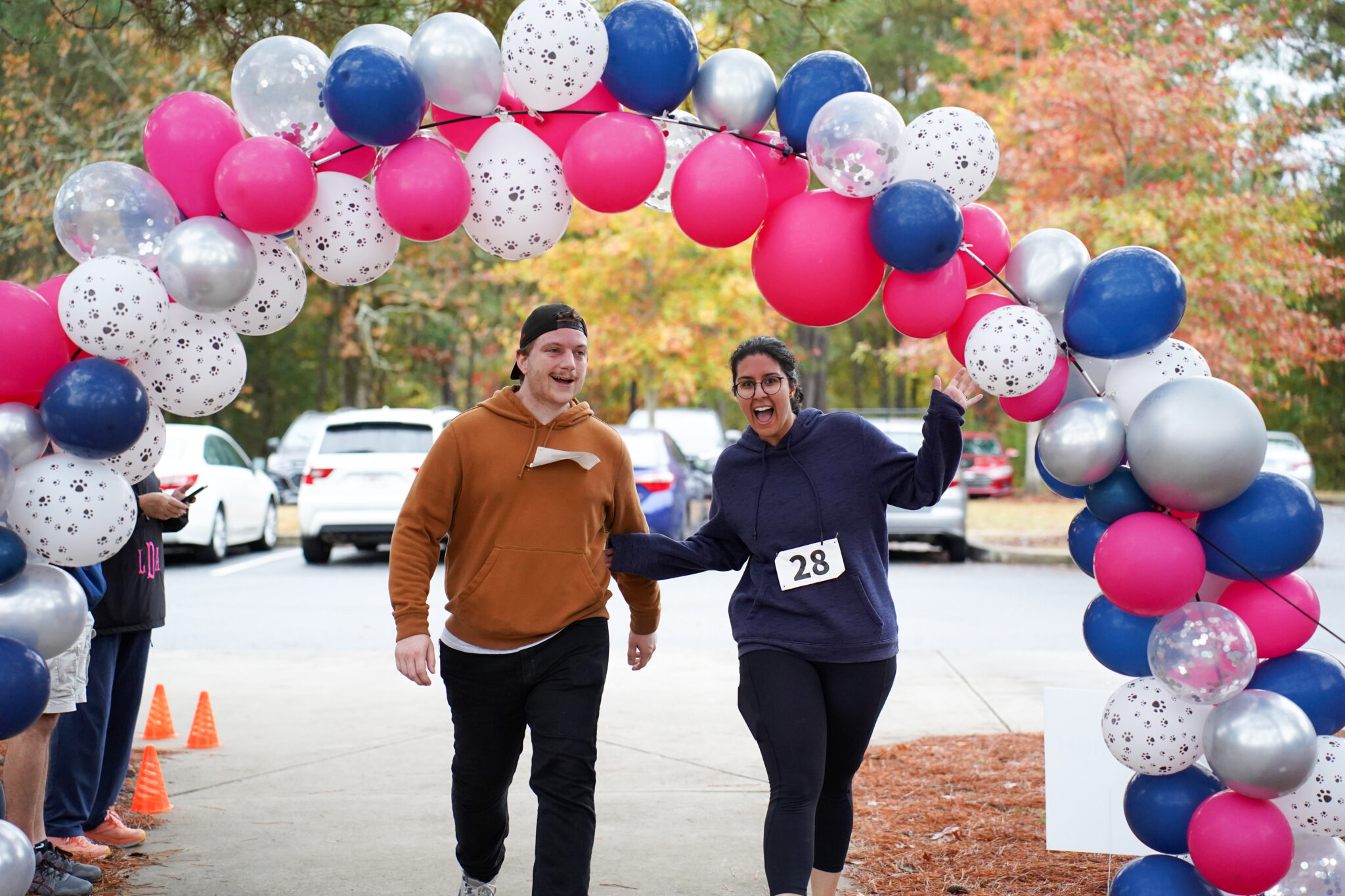 Two runners under a balloon arch.