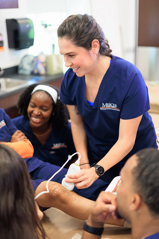 A Mercer student uses an ultrasound on a person's knee.