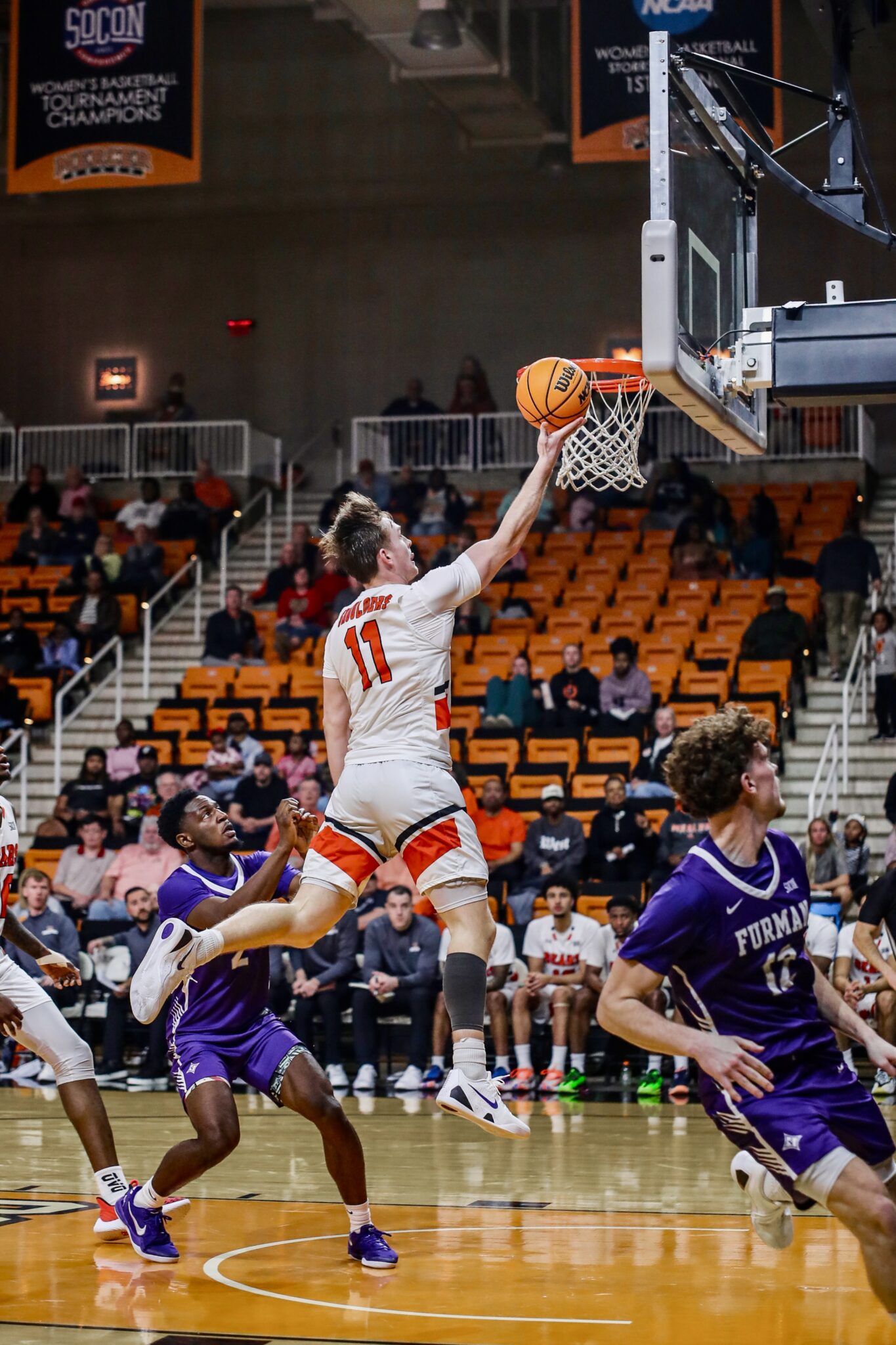 A Mercer men's basketball player jumps to shoot into the net.